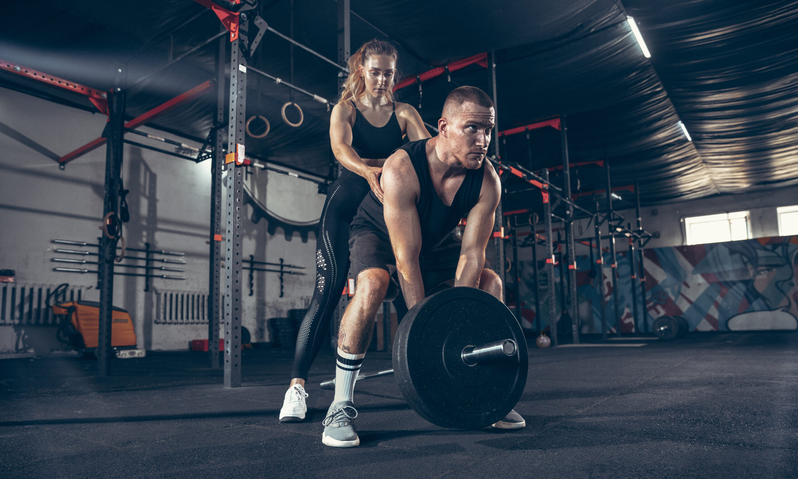 Caucasian young sporty couple workout in gym together. Concept of sport, activity, healthy lifestyle, strength and power.
